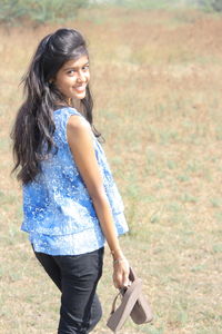 Portrait of smiling young woman standing against tree