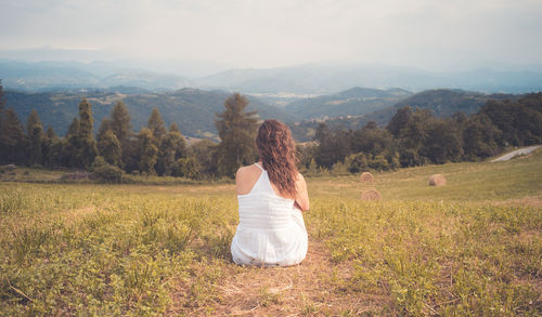 Rear view of woman sitting on field 
