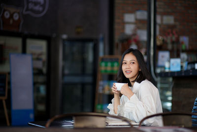 Smiling woman with coffee cup sitting in cafe