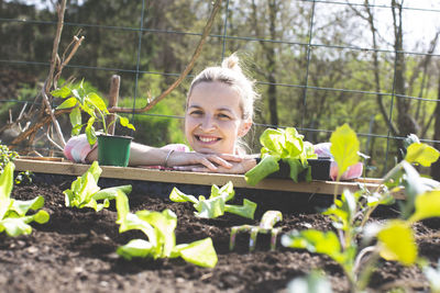 Smiling woman leaning on raised bed in yard