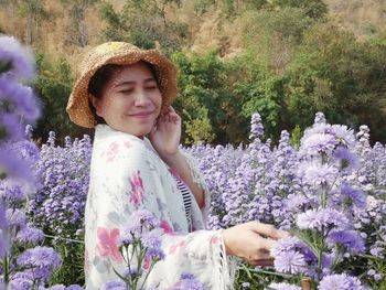 Portrait of smiling woman standing by purple flowering plants