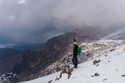 Full length of man standing on snow covered mountain ridge