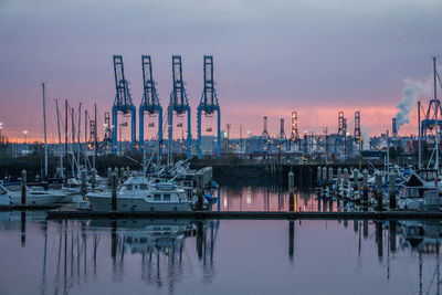 Sailboats moored at harbor against sky during sunset