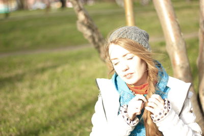 Smiling young woman holding umbrella in park