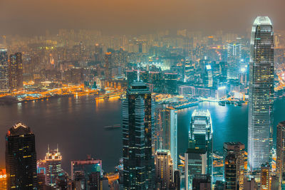 Aerial view of illuminated city by river against sky