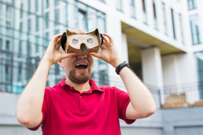 Man wearing virtual reality headset while standing against built structure