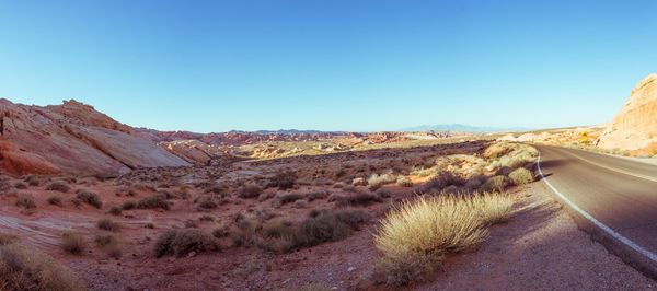 Road amidst desert against clear blue sky