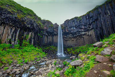 Scenic view of waterfall against sky