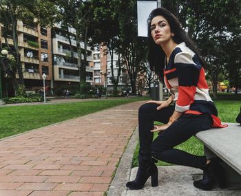 Young woman sitting on bench in park