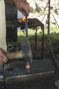 Close-up of manual worker hitting on molten metal in industry