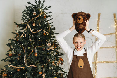 Funny man in front of christmas tree ready for celebration with gifts in bear mask and costume