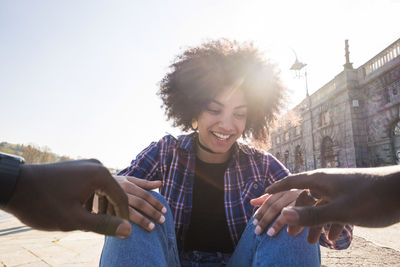 Cropped image of man hand reaching towards woman sitting on city street