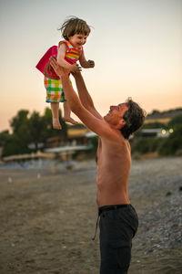 Father playing with daughter at beach