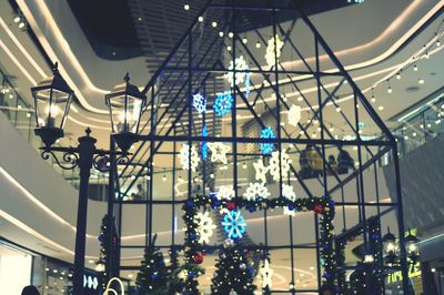 Low angle view of illuminated lights hanging from ceiling in shopping mall