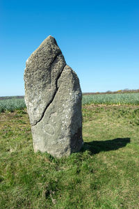 Rock on field against clear sky