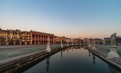 Reflection of buildings in city at sunset