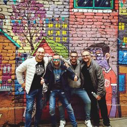 Full length of people standing against graffiti wall