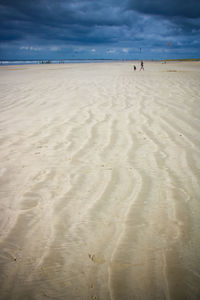 Scenic view of beach against cloudy sky during sunny day