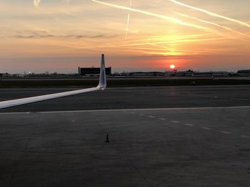 Airplane on runway against sky during sunset