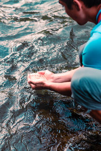 Side view of man holding water from flowing river