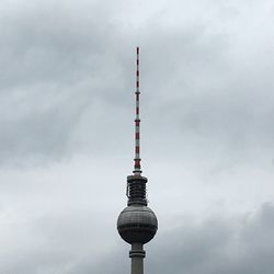 Low angle view of fernsehturm against cloudy sky