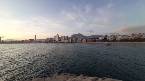 Sea and buildings against sky during sunset