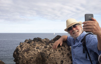 Senior man taking selfie against sea