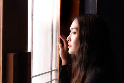 Thoughtful woman looking through window