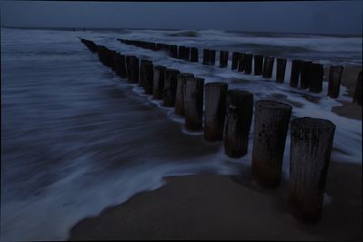 Wooden posts on beach against sky