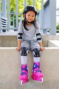 Portrait of girl with roller skater sitting on retaining wall
