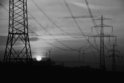 Low angle view of electricity pylon against sky at sunset