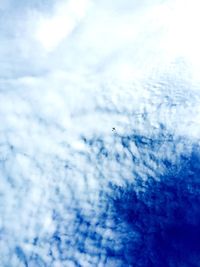 Low angle view of airplane flying against cloudy sky