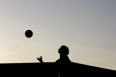 Low angle view of silhouette man with arms outstretched against sky during sunset