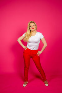 Portrait of young woman standing against red background