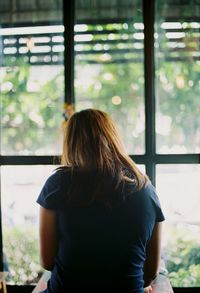 Rear view of woman standing against window