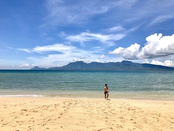 Woman standing on beach against sky