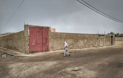 Side view of woman walking on road against sky
