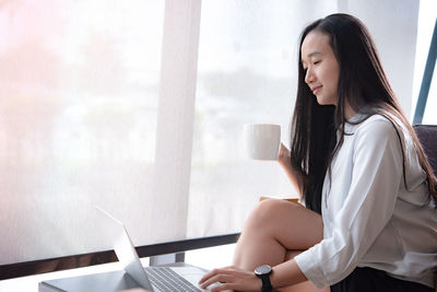 Side view of a young woman drinking coffee cup