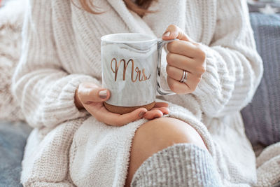 Midsection of a woman holdig cup. home, cozy, sweater.