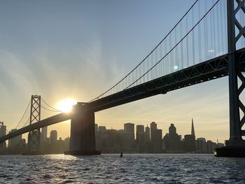 View of suspension bridge in city at sunset