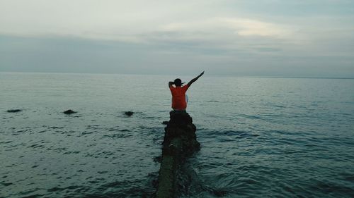 Man standing in sea against sky