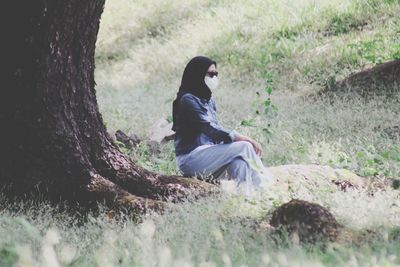 Side view of man sitting on tree trunk