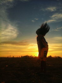 Silhouette woman standing on field against sky during sunset