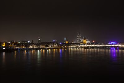 Illuminated cityscape by river at night