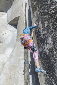 Climber looking at his feet in pink legging on the nose in yosemite