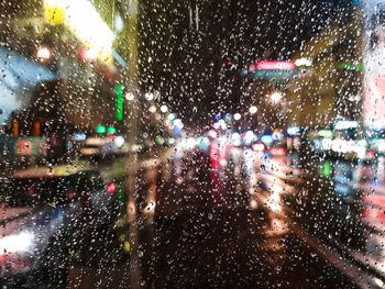 Illuminated city seen through wet glass window