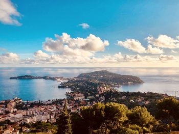 Aerial view of city by sea against sky