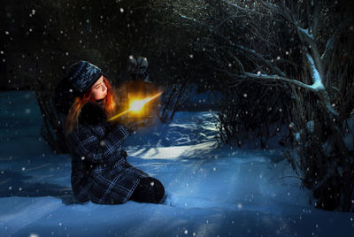 Pretty redhead girl holding lantern in winter forest