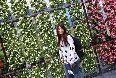 Smiling mid adult woman standing against plants