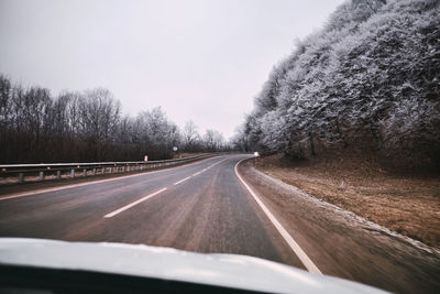 Road amidst trees seen through car windshield